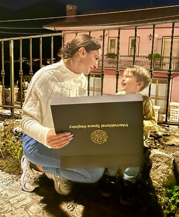 Mother and son smiling at each other whilst holding their name a star gift box